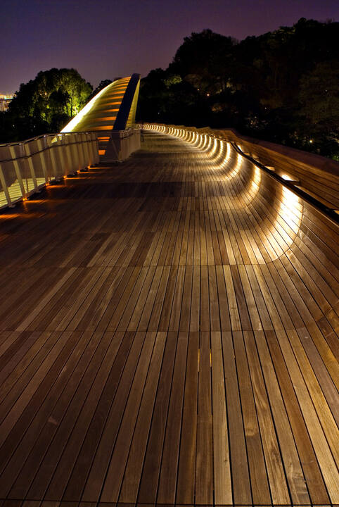 Warm concealed lighting washing the curved timber benches and deck of Henderson Waves